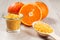 Cut orange with two whole oranges, glass bowl and wooden spoon w
