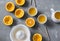 Cut oranges, fresh orange juice, manual citrus juicer on a grey table, top view.