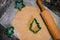 Cut out gingerbread cookie form in the form of a Christmas tree from raw dough on parchment baking paper on a dark background.