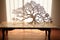 cut-out paper tree with dancing shadows on a wooden table