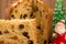 a cut panettone and a slice with christmas ornaments on brown background