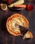 The cut piece of Vegetable Spiral tart with zucchini, eggplant, carrot on wooden background