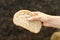 A cut piece of white homemade bread in a woman& x27;s hand on a dark background. World food crisis, food shortage, hunger