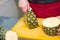 Cut the pineapple with a knife on a clear plastic paste on a stone cutting board. Pineapple slicing prepared for eat.man