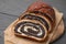 Cut poppy seed roll on grey wooden table, closeup. Tasty cake