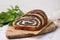 Cut poppy seed roll on white marble table, closeup. Tasty cake