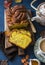 Cut the pumpkin brioche cinnamon on rustic wooden chopping board, tea with milk and a teapot on a blue background, top view.