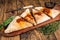 Cut and sliced Calzone closed pizza with ham and cheese on wooden board with hot tomato sauce. wooden background. Top