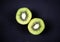 Cut, sliced fresh Kiwi fruit isolated, overlay on acrylic black scratchy grunge painting on canvas background. Overhead, top view