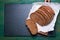 Cut in slices loaf of bread on a cut board on a green vintage wooden background with place for text