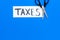 Cut taxes concept. Sciccors cut paper with word Taxes on blue background top view space for text