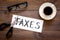 Cut taxes concept. Sciccors cut paper with word Taxes on dark wooden background top view