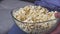 Cut view and close up of man taking popcorn from transparent bowl. Tasty delicious crispy fast food.