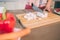 Cut view of female`s hands cutting white chees into pieces on desk. She uses knife. There are carrot and pepper on plate.