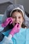 Cut view hands in latex gloves to floss child front teeth. Woman hold dental tools beside.