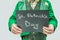 Cut view of man in green suit holding dark tablet with written words St. Patrick`s day. on grey background.