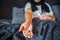 Cut view of young man sitting on bed and holding lots of pills on hand. Guy has glass of water as well. Sick man has