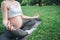 Cut view of young pregant woman show belly in park outside. She sit on yoga mate in lotus pose and meditate. Model keep