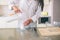 Cut vuew of girl wears white shirt. She stands in kitchen at table. Woman is pouring in some milk into glass cup. There