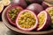 Cut and whole passion fruits maracuyas in wooden bowl, closeup