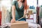 Cutaway view of a young businesswoman, packing a box with tape, for a shipment from her online clothing shop. Young
