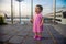 Cutcute toddler baby in a pink dress cries frightenedly lost at the airport. airplanes in background in blur