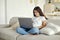 Cute 12s girl use laptop sit on sofa in living room