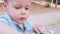 Cute 3 year old child playing with pebbles on wooden table outdoors. Close up head shot