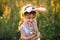 Cute 5-year-old girl with rabbit ears gently hugs a toy rabbit in nature in a blooming field in summer with golden sunlight.