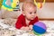 Cute 6 months little baby boy with curiosity expression on his face surrounded by colourful toys