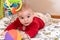 Cute 6 months little baby boy with curiosity expression on his face surrounded by colourful toys