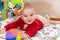 Cute 6 months little baby boy with curiosity expression on his face surrounded by colourful toys