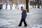 Cute 6 years old caucasian boy  wearing knit hat with fur pompom  walking on slushy snow surface. leaving watery footprints in par