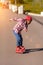 Cute active african american boy on rollers skates at asphalt road in summer sunset. Roller kid learn first steps
