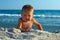 Cute active baby boy playing in sand on beach