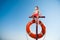 Cute active little kid rescuer in red shorts sitting on post with orange lifebuoy during summer beach safe vacation leisure with