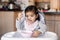 Cute adorable Asian Chinese kid girl sitting in high chair eating soup with spoon. Healthy eating for kids children. Toddler