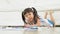 Cute adorable asian ethnic kid girl holding color pen drawing and painting, lying on warm floor, She is Having Fun and Laughs.