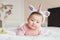 Cute adorable Asian mixed race smiling baby girl four months old lying on tummy on bed