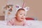 cute adorable Asian mixed race smiling baby girl four months old lying on tummy on bed in bedroom wearing unicorn headband horn a