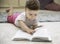 A cute adorable baby turns pages in a book on the carpet