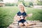 Cute adorable blonde girl playing pink guitar toy outdoors. Child playing music and singing song in park. Hobby activity for