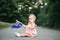 Cute adorable Caucasian baby girl waving Australian flag. Smiling child sitting on street road in park celebrating Australia Day