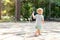 Cute adorable caucasian blond barefeet boy walking at home backyard holding hose pipe for watering garden. Child little