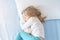 Cute adorable caucasian blond little toddler girl lying in bed on white pillow.Profile side view portrait of baby dreaming asleep