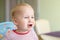 Cute adorable caucasian blond toddler boy sitting in high chair and crying while feeding. Upset unhappy child refuse to eat
