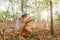 Cute adorable Caucasian girl kid looking at tree in forest through magnifying glass.