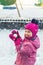 Cute adorable caucasian little girl winter portrait holding snowball in hands ready for snow fight at playground outdoor. Funny