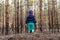 Cute adorable caucasian lonely toddler baby boy standing alone on hill during walk in fall coniferous pine woods at day