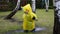 Cute adorable caucasian toddler boy in bright yellow raincoat and wellies playing alone at dirt muddy puddle during cold